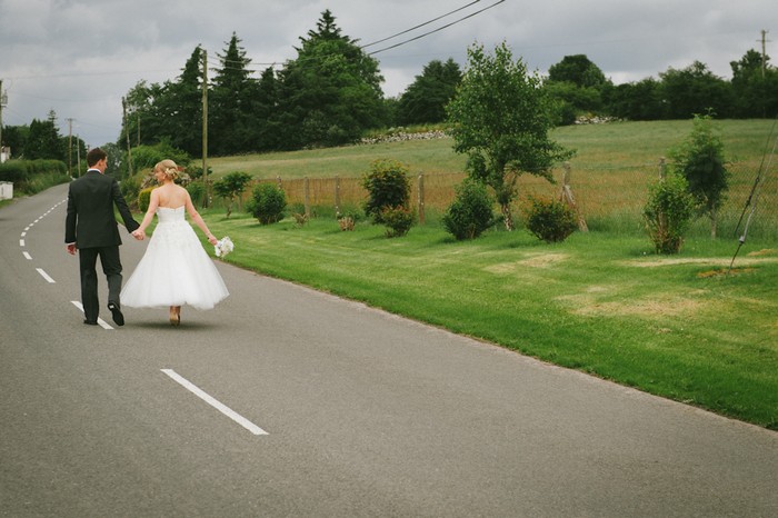 bride and groom walking down a road together 